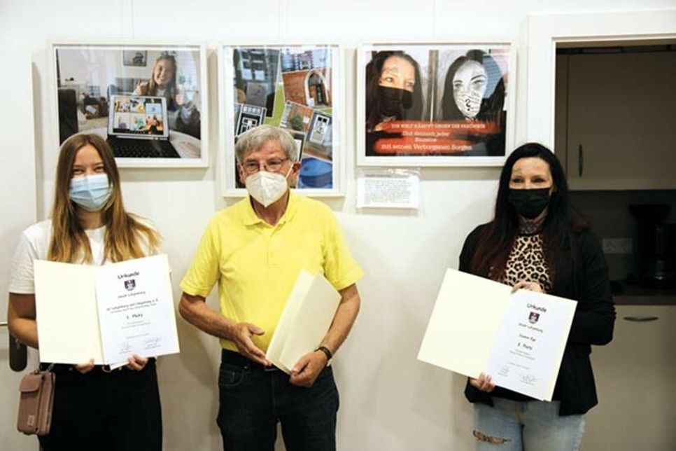 Die Preisträger Lea Kloth, Heinrich Ripke und Jasmin Ege vor ihren Fotos im Rahmen der Siegerehrung.
