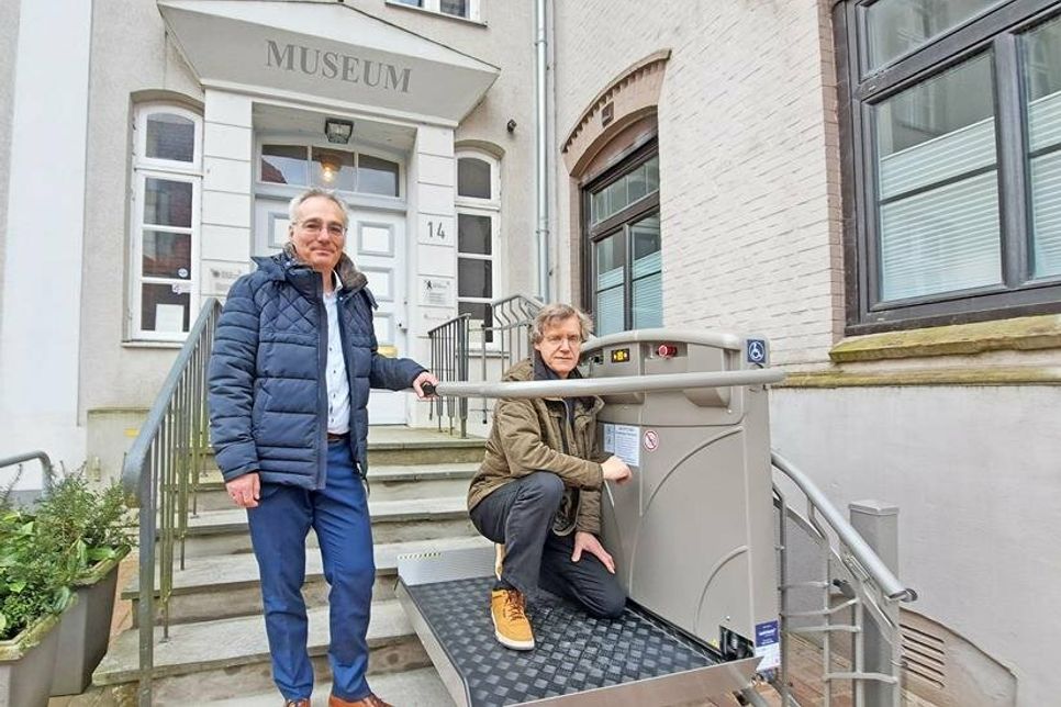 Bürgermeister Tim Brockmann (links) und Heimatvereinschef Axel Langfeldt präsentieren den neuen Außenlift am Eingang des Heimatmuseums.