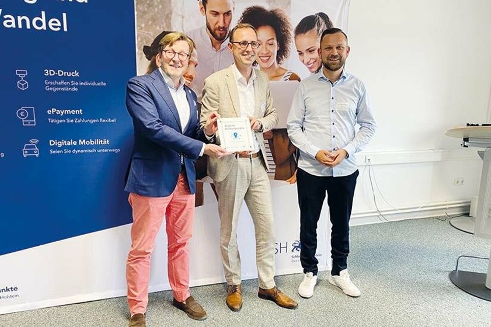 Bürgermeister Sven Partheil-Böhnke (links) und Göktug Keskin, Digitalisierungsbeauftragter der Gemeinde Timmendorfer Strand, erhalten aus den Händen von Dirk Schrödter, (Mitte) Chef der Staatskanzlei SH, die Auszeichnung.