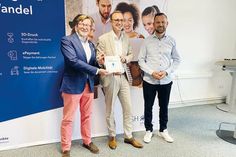 Bürgermeister Sven Partheil-Böhnke (links) und Göktug Keskin, Digitalisierungsbeauftragter der Gemeinde Timmendorfer Strand, erhalten aus den Händen von Dirk Schrödter, (Mitte) Chef der Staatskanzlei SH, die Auszeichnung.
