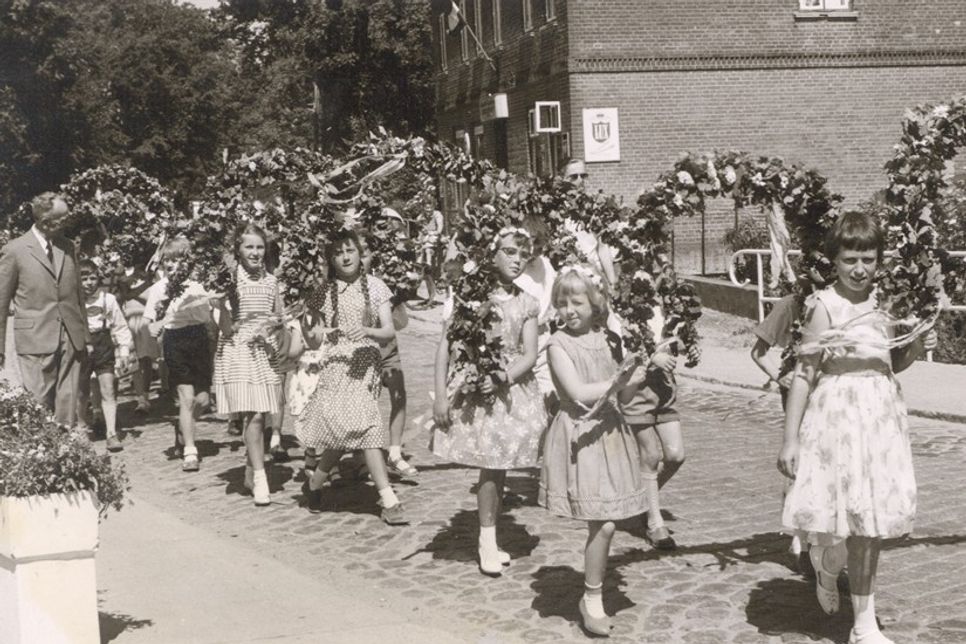 Festumzug beim Schul-Kinderfest vor rund 70 Jahren: Kinder ziehen mit Blumenkränzen durch das Dorf - damals noch über das Kopfsteinpflaster der heutigen B 501.