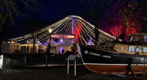 Bunte Lichter bilden ein „Festzelt“ über dem Weihnachtsmarkt auf der Festivalwiese, zu der man vorbei an liebevoll arrangierten Ausstellungs- und Spielmöglichkeiten gelangt.