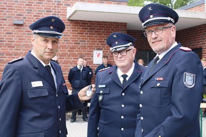 Statt des Schilds für die Außenwand nahm Ovendorfs Wehrführer Fabian Fuhrmann (li.) in Begleitung von Ostholsteins stellvertretendem Kreiswehrführer Lars Wellmann (re.) den kleinen Anhäger von Klaus Seemann entgegen.