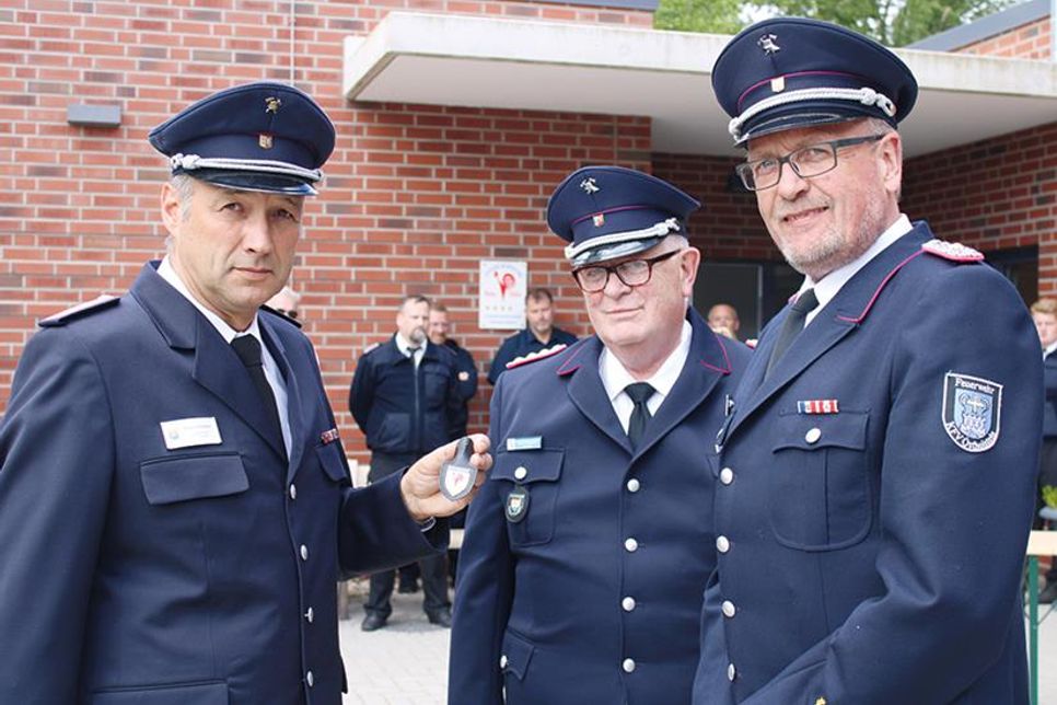 Statt des Schilds für die Außenwand nahm Ovendorfs Wehrführer Fabian Fuhrmann (li.) in Begleitung von Ostholsteins stellvertretendem Kreiswehrführer Lars Wellmann (re.) den kleinen Anhäger von Klaus Seemann entgegen.
