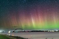 Magisches Zusammenspiel: Torge Zdunecks Leserfoto präsentiert die Fehmarnsundbrücke unter einem funkelnden Sternenhimmel und Nordlichtern.
