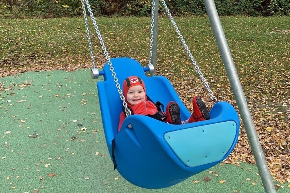Die kleine Tomke freut sich sichtlich über die neue Babyschaukel auf Kellenhusens neuem Inklusionsspielplatz.