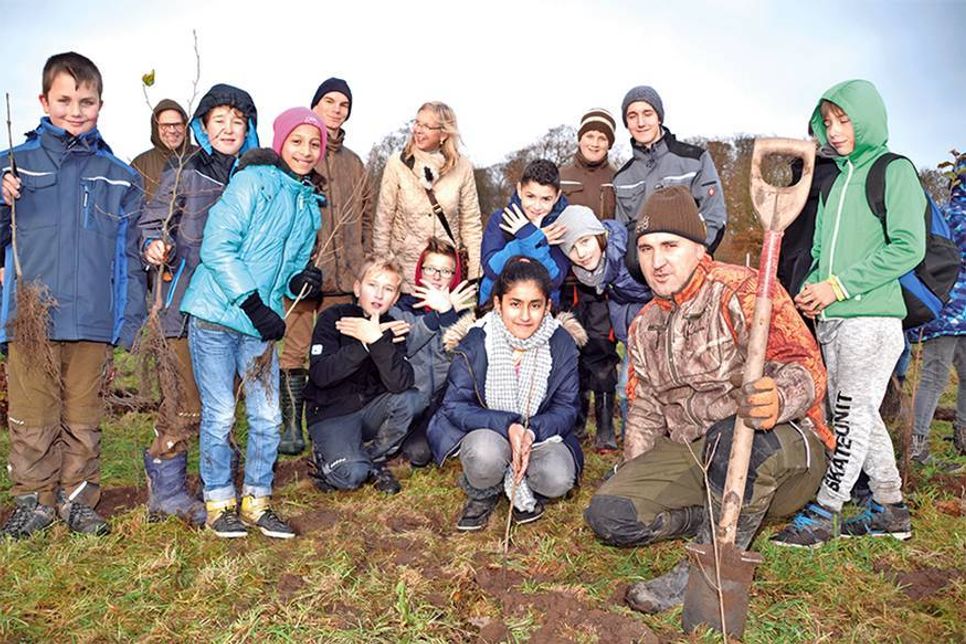 Begaj aus der Klasse 5 c und ihre Mitschüler hatten viel Spaß beim Einpflanzen der kleinen Bäume, hier mit Unterstützung von Forstarbeiter Avni Hajrizi. (Foto: René Kleinschmidt)