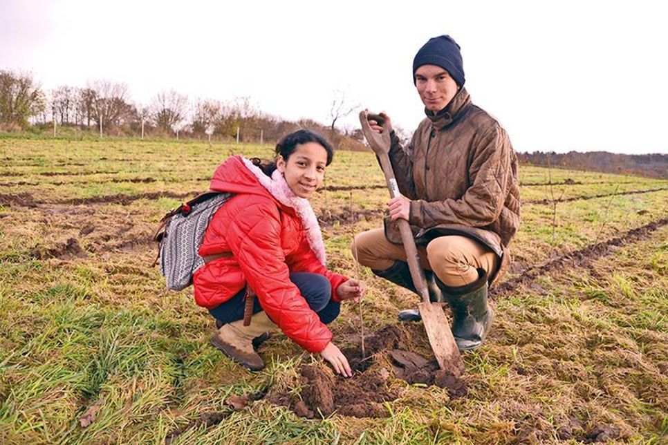 Nour aus der Klasse 5 c pflanzt mit Hilfe von Hauke Klies vom Land-, Wald- und Umweltausschuss der Kirchengemeinde Gleschendorf „ihren“ Baum ein. (Foto: René Kleinschmidt)