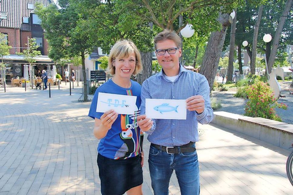 Christine Knebelkamp von der TSNT und Tourismuschef Joachim Nitz zeigen einige Vorlagen, die als Straßenmalerei auf dem Niendorfer Balkon entstehen sollen. (Foto: TSNT GmbH)
