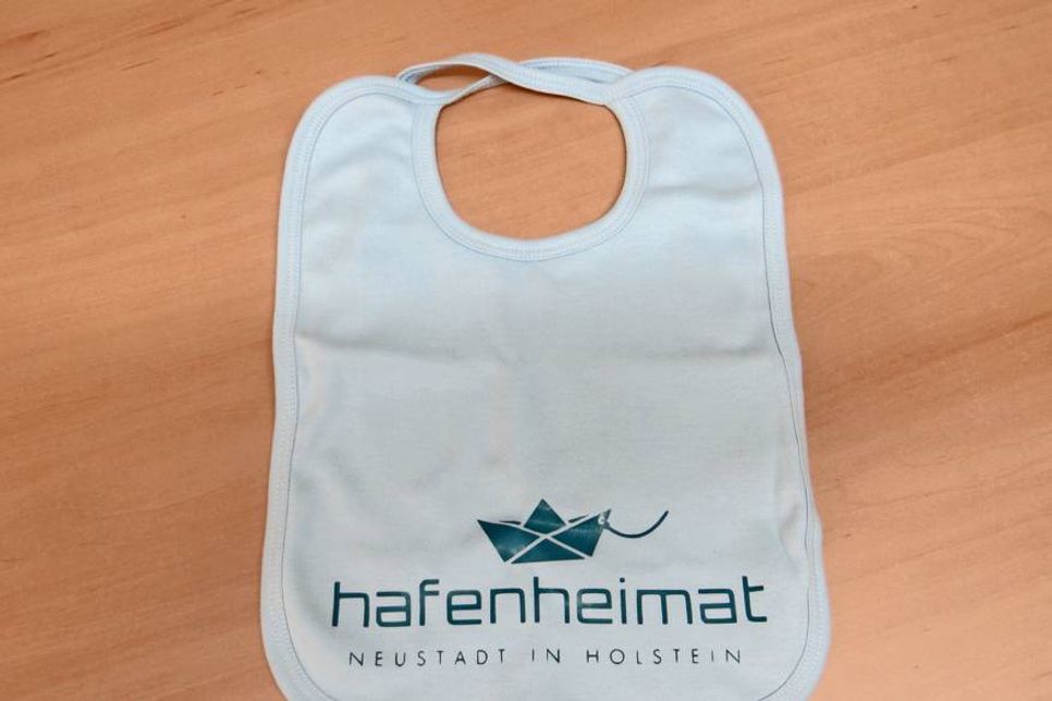 Die hafenheimat-Lätzchen aus Bio-Baumwolle kosten 9,90 Euro und sind auf Vorbestellung in verschiedenen Farben im Geschäft ZwergNase in der Brückstraße 2 in Neustadt erhältlich.