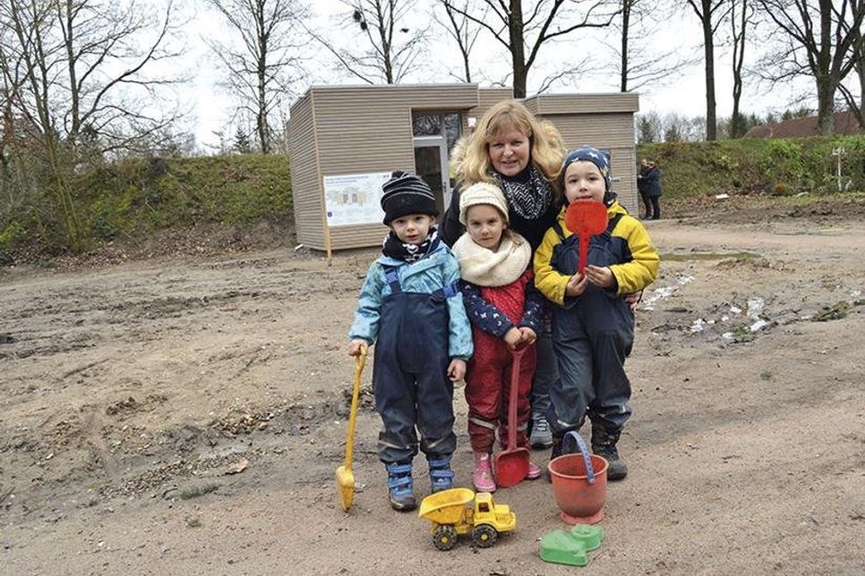 Emilio (3, v.l.), Levina (4) und Maximilian (4) sind drei der ersten Kinder in der neuen Waldkindergartengruppe. Gemeinsam mit Einrichtungsleiterin freuen sie sich über ihre tolle neue Schutzhütte (im Hintergrund). (Foto: Setje-Eilers)