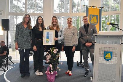 Die Schülersprecherinnen der GGS-Strand, Lilian Haselow (Mitte) und Maria Timani, nehmen mit Initiatorin und Lehrerin Bettina Kammholz (links) den Umwelt- und Klimaschutzpreis aus den Händen von Bürgervorsteherin Anja Evers entgegen. Darüber freut sich auch Bürgermeister Sven Partheil-Böhnke.