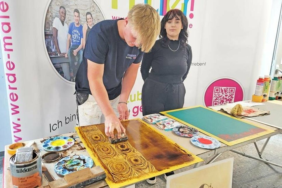 Justin Bong zeigt gemeinsam mit Marlene Palm, wie die Holzmaserungstechnik funktioniert