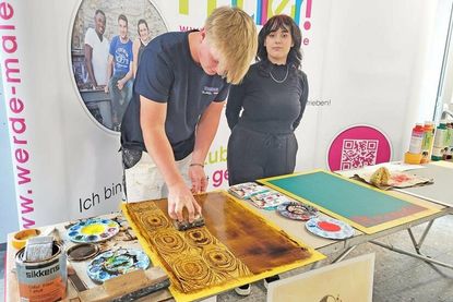 Justin Bong zeigt gemeinsam mit Marlene Palm, wie die Holzmaserungstechnik funktioniert