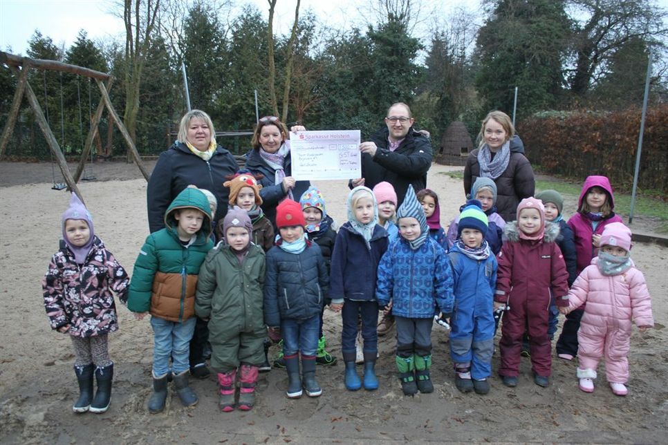 Übergabe der Spende auf dem Spielplatz des Kindergartens mit Theresa Kurth, Sachbearbeiterin Kindergärten beim Amt Lensahn, Kindergartenleiterin Carola Kollwitz, Jan Grimm (hi. v. lks.) sowie einigen Kindern.
