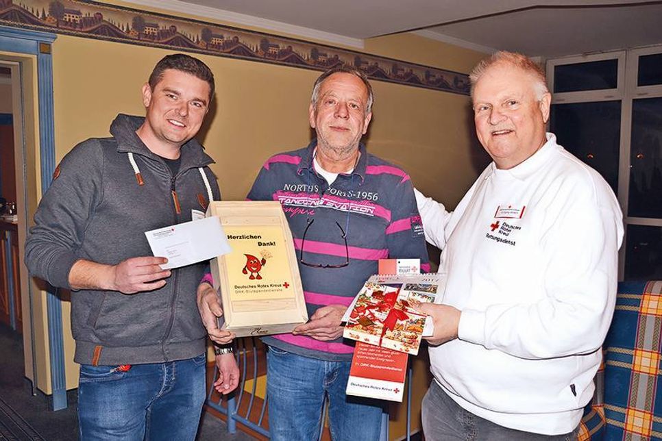 Till Quint, Referent für Öffentlichkeitsarbeit beim DRK-Blutspendedienst Nord-Ost, und Wolfgang Ahlisch (re.), 1. Vorsitzender des DRK-Ortsvereins Gemeinde Scharbeutz, bedanken sich bei Jubiläumsspender Jürgen Strunk mit Präsenten. (Foto: René Kleinschmidt)