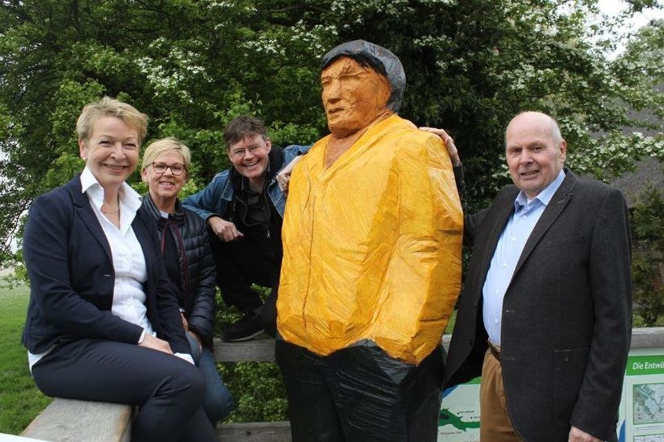 Der „Reisende“ in greller Kapuzenjacke auf der Aussichtsterrasse des Paasch-Eyler-Platzes, umrahmt von Claudia Reshöft, 2. Vorsitzende Landkunststück, Kirsten Sköries, Vorsitzende des Tourismusausschusses, Bildwerker Johannes Caspersen und Bürgermeister Volkert Stoldt.