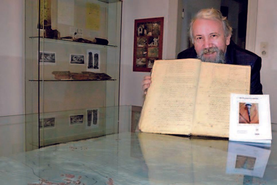 Volker Liebig präsentiert das alte Protokollbuch der Scheiben-Schützengilde Preetz.