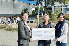 Die stellvertretende Hoteldirektorin Manja Brandt (Maritim Seehotel, links) übergibt vor dem ersten Sonnensegel den obligatorischen Spendenscheck an Schulleiterin Esther Passig (Mitte) und Kunstlehrerin Christina Geberbauer.