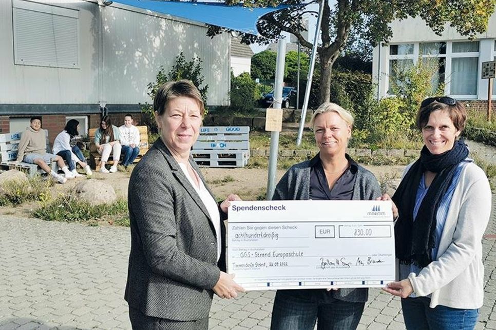 Die stellvertretende Hoteldirektorin Manja Brandt (Maritim Seehotel, links) übergibt vor dem ersten Sonnensegel den obligatorischen Spendenscheck an Schulleiterin Esther Passig (Mitte) und Kunstlehrerin Christina Geberbauer.