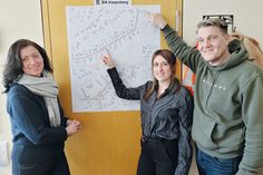 Bürgermeisterin Bettina Schäfer (links), Veronika Ruppert und Dirk Dibbern vom Bauamt der Gemeinde vor dem Plan für den 3. Bauabschnitt „Kiepenberg“.