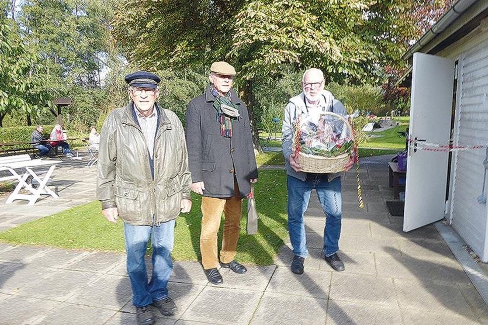 Eckhard Mix vom Umweltbeirat (l.) und Klaus Nentwig, 1. Vorsitzender des Gemeinnützigen Bürgervereins Bad Schwartau, überreichen Helmuth Kirsten zum Dank für seine Verdienste um den beliebten Minigolfplatz einen Präsentkorb.