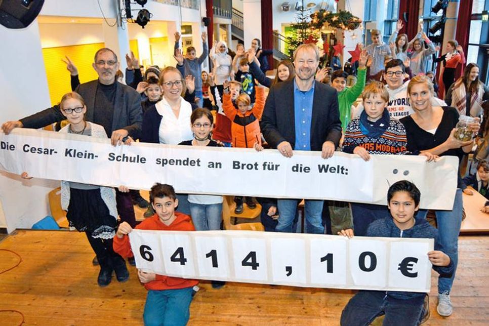 Vor ihren Mitschülern enthüllen Leslie (v.l.), Maxi, Lydia, Tim und Bryan mit Schulleiter Georg Krauß (hinten l.), den Lehrkräften Juliane Bremer und Christin Tiedemann sowie Torsten Nolte von „Brot für die Welt“ die Plakate mit der stolzen Spendensumme. (Foto: Stefan Setje-Eilers)