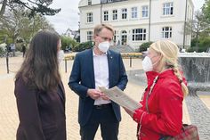 Anne Zwilling aus Niendorf/Ostsee (rechts) überreicht Ministerpräsident Daniel Günther (CDU) auf dem Timmendorfer Platz eine Petition zur Öffnung der Promenade für fahrradfahrende Schulkinder, links Melanie Puschaddel-Freitag.