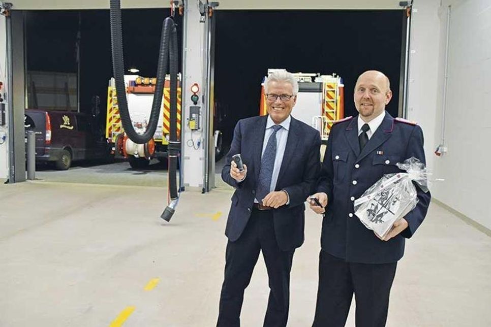 Mit Knopfdruck auf die Fernbedienungen öffnen sich die Rolltore im neuen Anbau des Feuerwehrgerätehauses: Ortswehrführer Sven Reimers und Bürgermeister Volker Owerien probieren es zur offiziellen Einweihung aus.