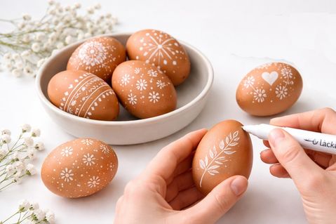 Feine Linien, kleine Blüten: Mit einem weißen Lackstift entstehen auf braunen Eiern schlichte, elegante Muster.