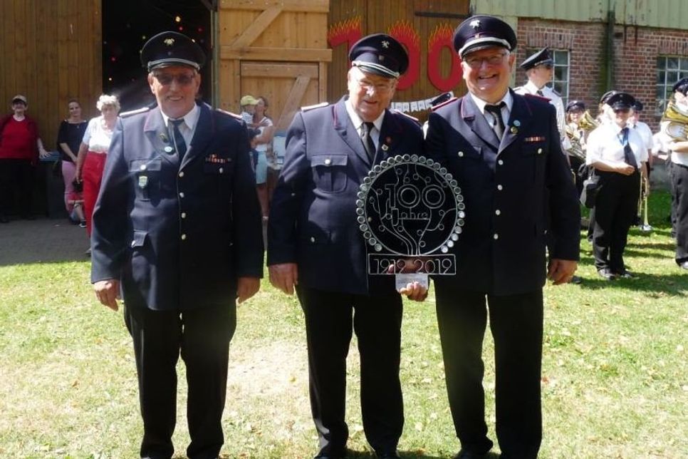 Joachim Huckfeldt (Mitte) überreichte Wolfgang Vietze und Thorsten Ahrens (v. lks.) von der Wehr ein selbst gefertigtes Emblem.