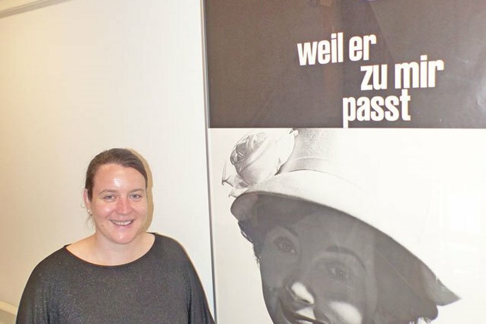 Katrin Maibaum aus dem Team des Ostholstein Museums neben der VW Werbung aus den 60ern – natürlich für das Kultauto der Deutschen, den Käfer.