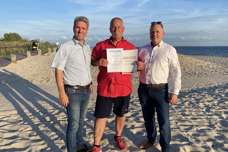 Heinz Gerlach (Mitte) wird von Klaus Holger Hecken (re.) und Stephan Reil (lks.) für sein langjähriges, ehrenamtliches Engagement im Wasserrettungsdienst ausgezeichnet.