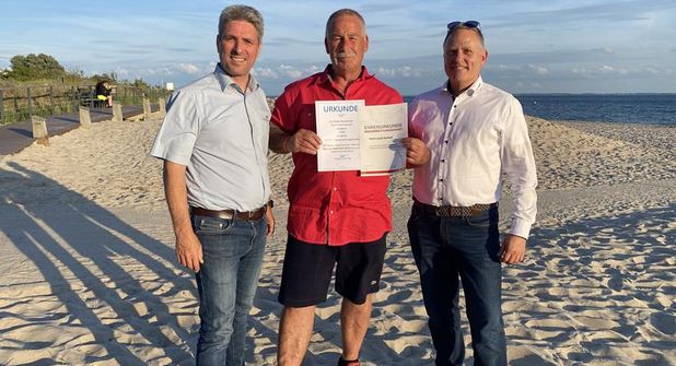 Heinz Gerlach (Mitte) wird von Klaus Holger Hecken (re.) und Stephan Reil (lks.) für sein langjähriges, ehrenamtliches Engagement im Wasserrettungsdienst ausgezeichnet.