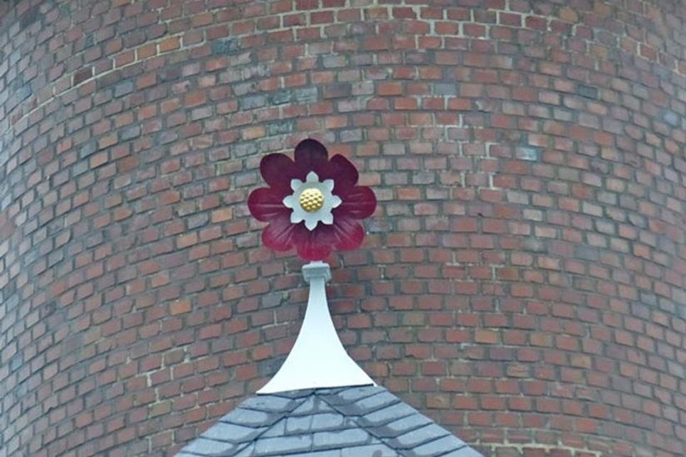 Auf dem Dachvorsprung glänzt die kleine metallene Rose wieder in ihrem alten Glanz.