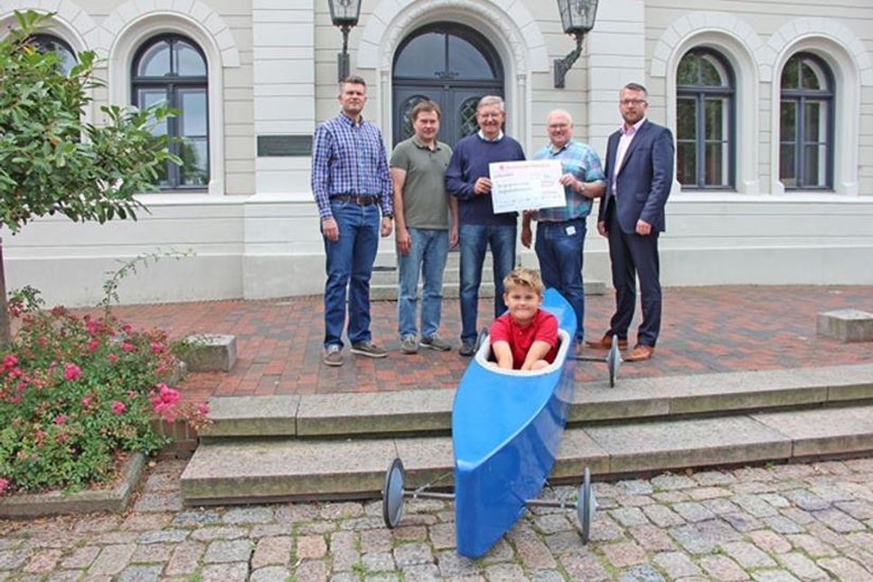 Seifenkisten-Rennfahrer Alexander Jubel, Christian Kahl und Peter Jubel von der Bürgergemeinschaft Oldenburg, Siegmar Witzleben sowie Uwe Wolters vom Automobil-Club Oldenburg e.V. im ADAC und Oldenburgs 1. Stadtrat Jens Junkersdorf haben sich am Donnerstag zur symbolischen Spendenübergabe vor dem Oldenburger Rathaus versammelt.