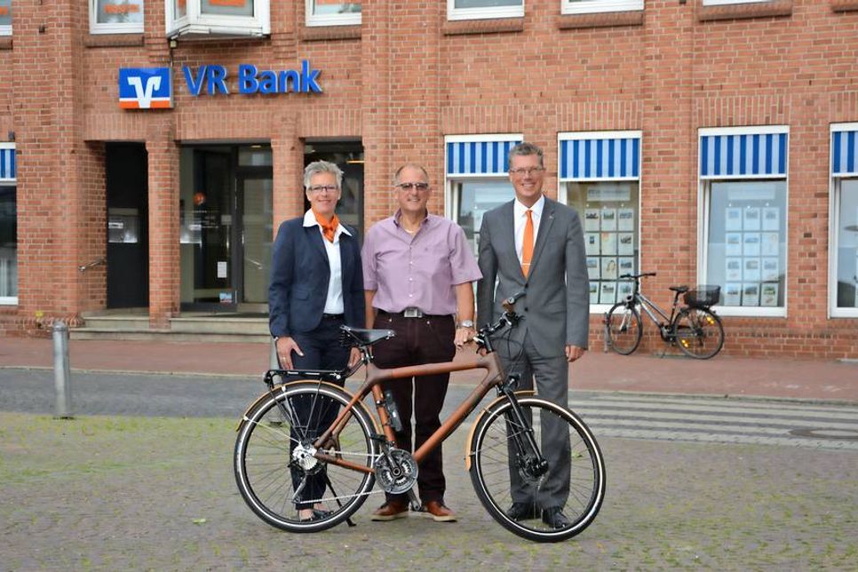 Wilfried Dettmering (Mitte) aus Neustadt hat mit seinem Gewinnsparlos ein Bambusfahrrad gewonnen, das ihm von Kundenberaterin Nicole Hopp und Regionalleiter Ulf Braune übergeben wurde.