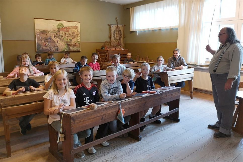 Gerrit Gätjens (re.) erhob in seiner Rolle des Dorfschullehrers von damals ermahnend den Rohrstock vor der dritten Klasse der Friedrich-Hiller-Schule. Körperliche Strafen sind heute aus der Schule verschwunden, drohten im ausgehenden 19. Jahrhundert jedoch selbst für kleinste Vergehen wie unsaubere Finger.
