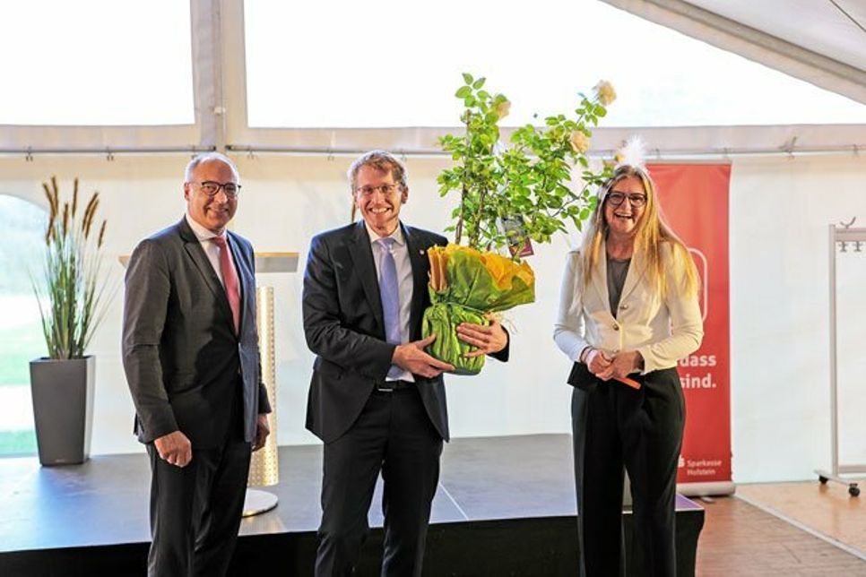 Kristina Buchwald, Vorstandsmitglied des Unternehmensverbands Ostholstein-Plön, überreichte Ministerpräsident Daniel Günther eine Rose aus dem Buchwald Pflanzencenter. Auf dem Bild: Thomas Piehl, Vorsitzender des Vorstands der Sparkasse Holstein, Ministerpräsident Daniel Günther (CDU) und Lydia Bahn, Vorstandsvorsitzende des Unternehmensverbandes Ostholstein-Plön