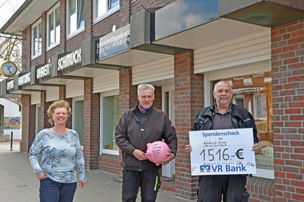 Die Bezirksschornsteinfeger Kay Habighorst (r.) und Jens Willrodt sowie Mitarbeiterin Petra Wiendlocha präsentieren den symbolischen Spendenscheck. Mit dem Geld werden die jungen Patienten auf der Kinderkrebsstation der Kieler Uniklinik unterstützt.
