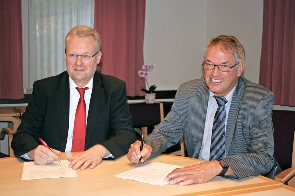 Amtsvorsteher Klaus Winter (re.) und Sven Thomsen von der Autokraft GmbH bei der Unterzeichnung des Kooperationsvertrags.