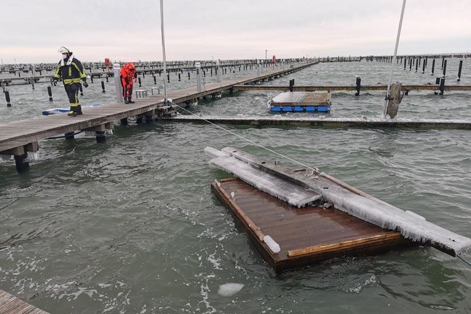 Einsatzkräfte sichern eine losgerissene schwimmende Arbeitsplattform im Hafenbecken.