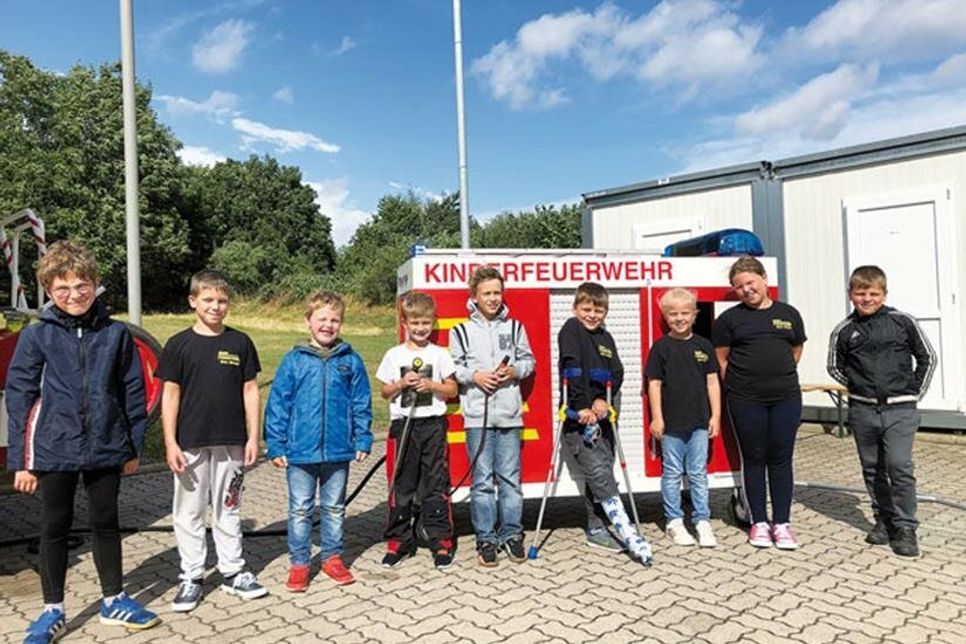 Kinderfeuerwehr-Mitglieder vor ihrem Fahrzeug.