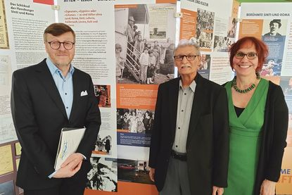 Timmendorfer Strands Bürgermeister Sven Partheil-Böhnke, Matthäus Weiß, Vorsitzender des Landesverbands der Sinti und Roma (Mitte), und Geschichtslehrerin Andrea Finke-Schaak vor Tafeln der Wanderausstellung im OGT.