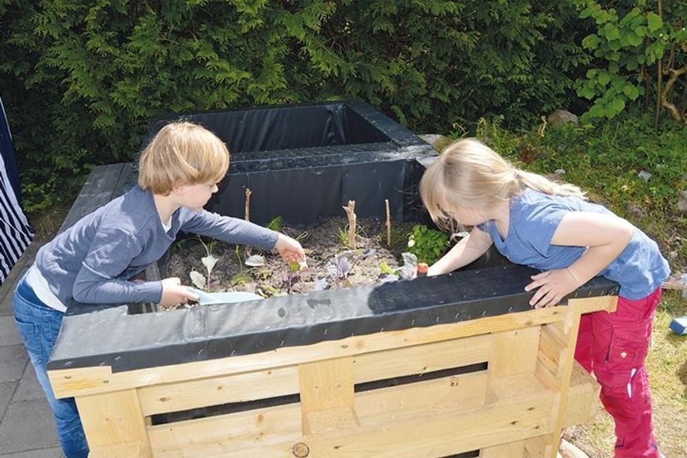 Die kleinen Pansdorfer Max und Hannah machen sich an dem aus recycelten Euro-Paletten gefertigten Hochbeet an die Arbeit.
