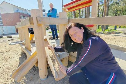 Bürgermeisterin Bettina Schäfer testet die Sandrinne und Uwe Jahnke, Beauftragter für Menschen mit Beeinträchtigungen (im Hintergrund), benutzt den Sandkran.