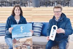 Timmendorfer Strands Marketingleiterin Silke Szymoniak und Tourismuschef Joachim Nitz präsentieren die Plakate und Türhänger mit der Aufschrift „Strand in Sicht – Schön, dass ihr da seid“, die zur Gäste-Begrüßung hergestellt wurden und von der TSNT GmbH kostenlos an die Betriebe gegeben werden.