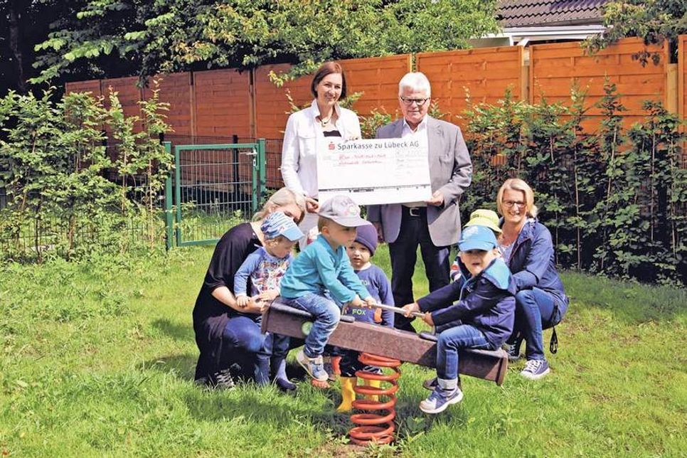 Lebenshilfe-Geschäftführerin Susanne Voß (l.) dankte Lions-Club-Präsident Manfred Riemer für die 2000-Euro-Spende. Paul und Mika (r.)  probierten die frisch montierte Doppelwippe gleich einmal aus. Ida, Emil und andere Kinder  schauten zu,  beaufsichtigt von Erzieherin Lisa Schimanski (l.) und Tagesstättenleiterin Melanie Müller. (Text + Foto: Rüdiger Wenzel)