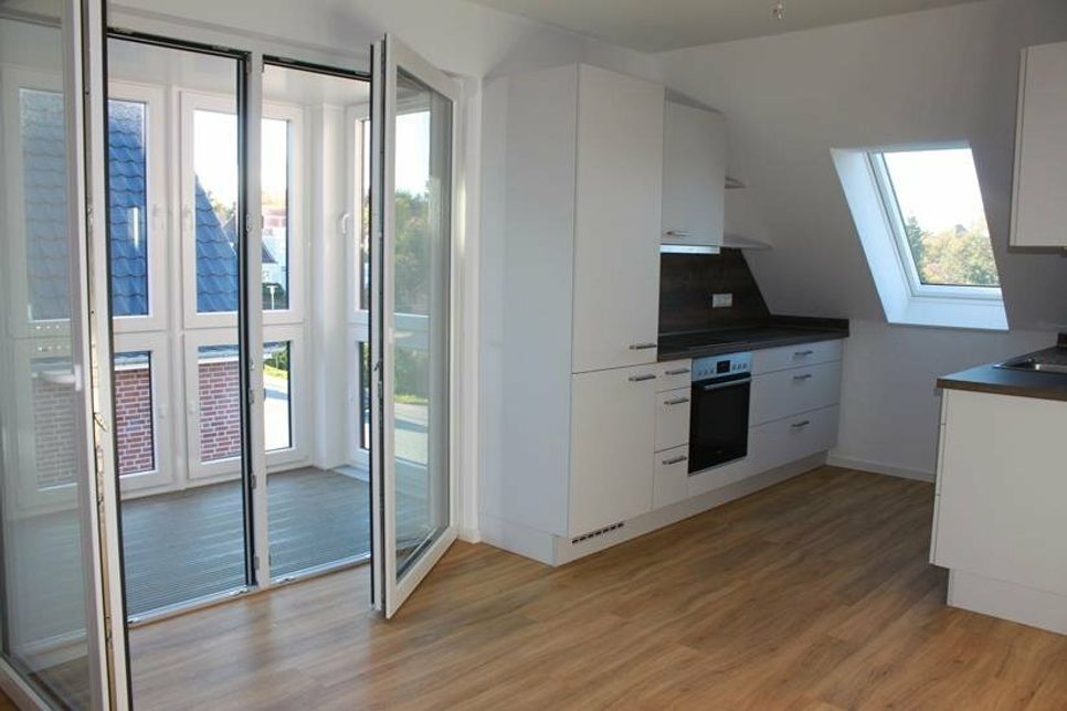 Blick auf die hochwertigen Einbauküchen und den Zugang zum Wintergarten. Die Verglasung sorgt für Extra-Schallschutz.