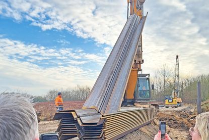 An der Straßenböschung wird zurzeit eine Spundwand in den Boden gerammt.